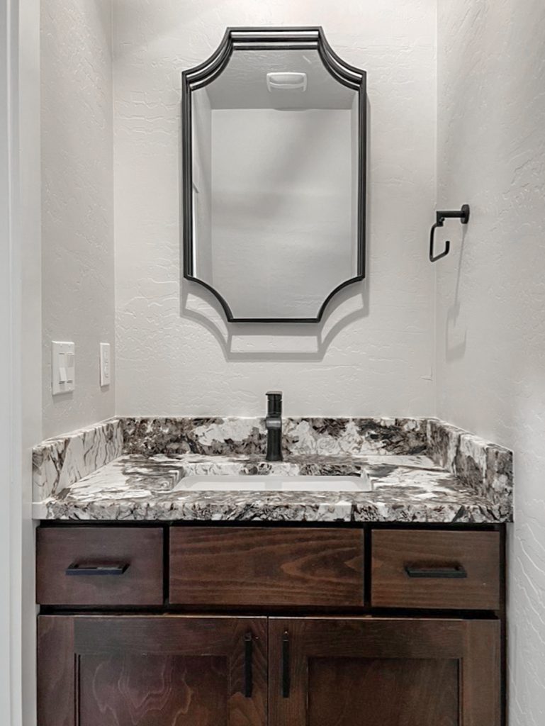 A bathroom with marble counter tops and a mirror.
