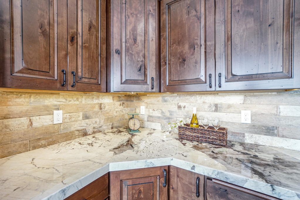 A kitchen with wood cabinets and marble counter tops.