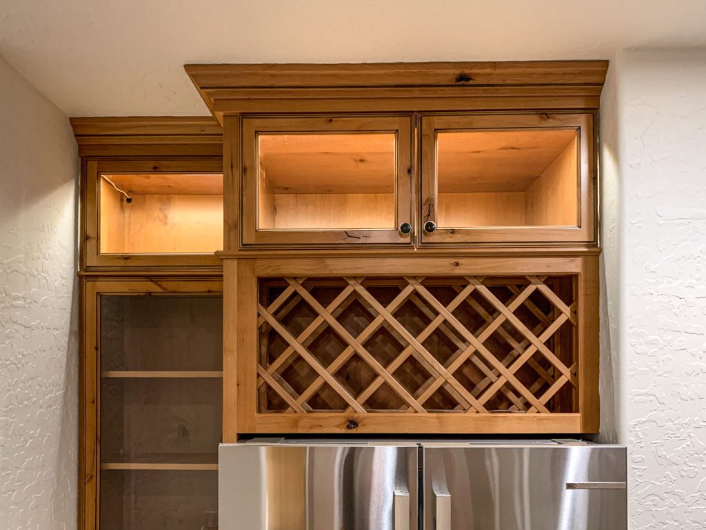 A kitchen with a refrigerator and a wine rack.