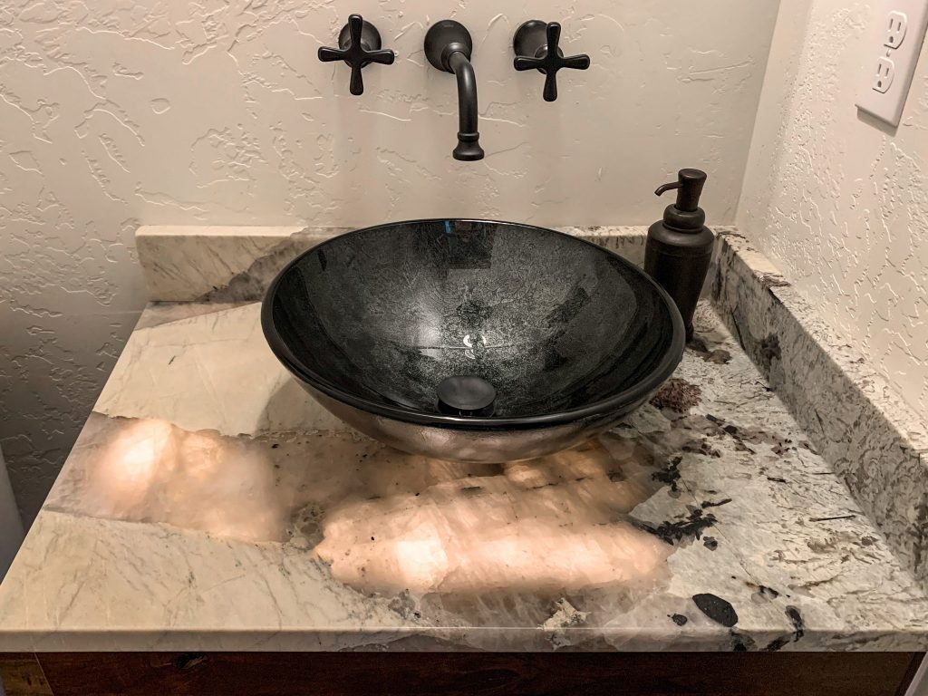 A black marble sink in a bathroom.