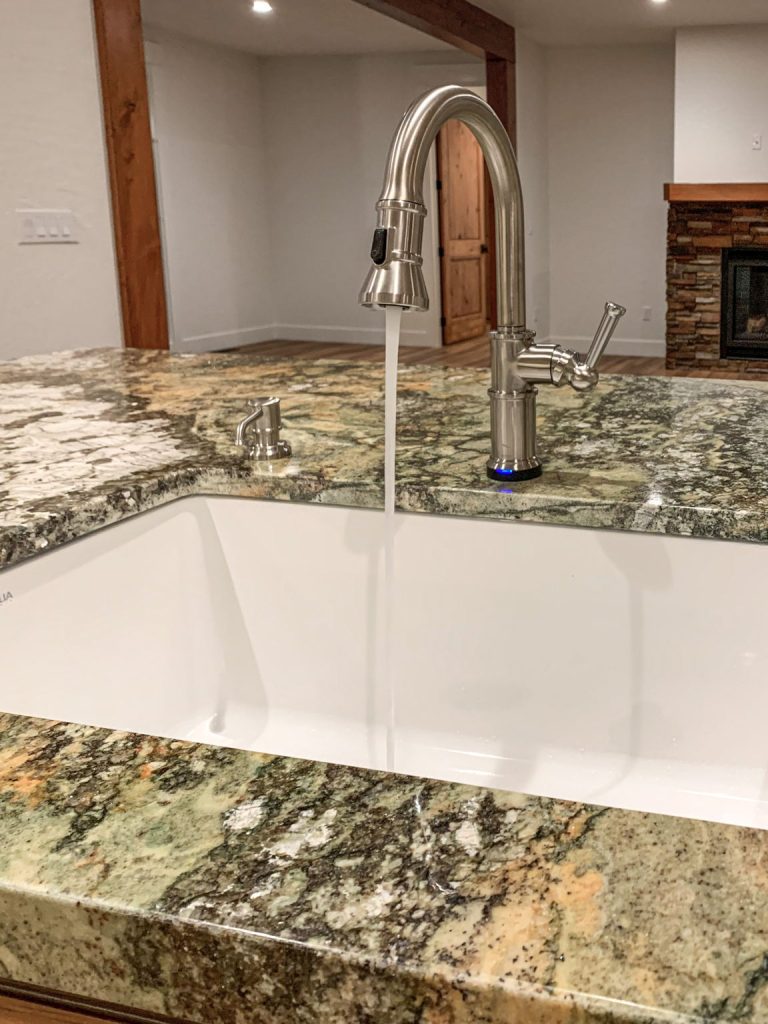 A kitchen sink with granite counter tops and a fire place.