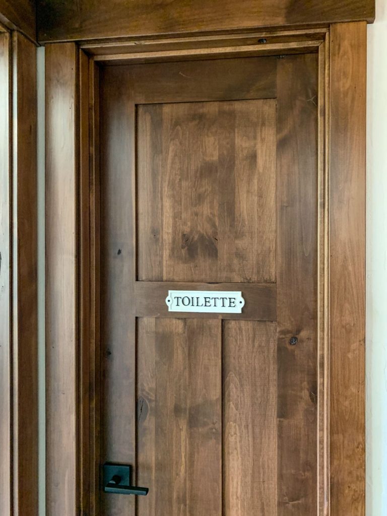 A bathroom with a wooden door and a toilet.