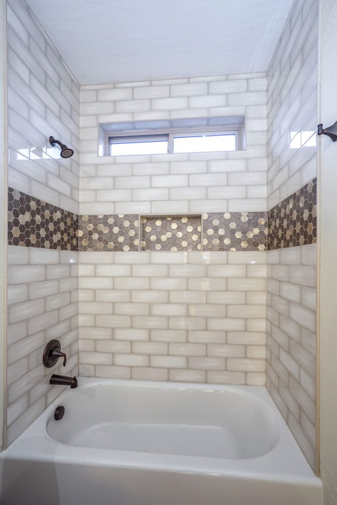 A bathroom with a tub and tiled walls.
