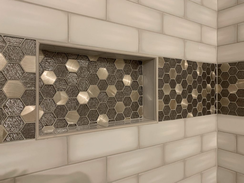 A bathroom with a tiled shower with hexagonal tiles.