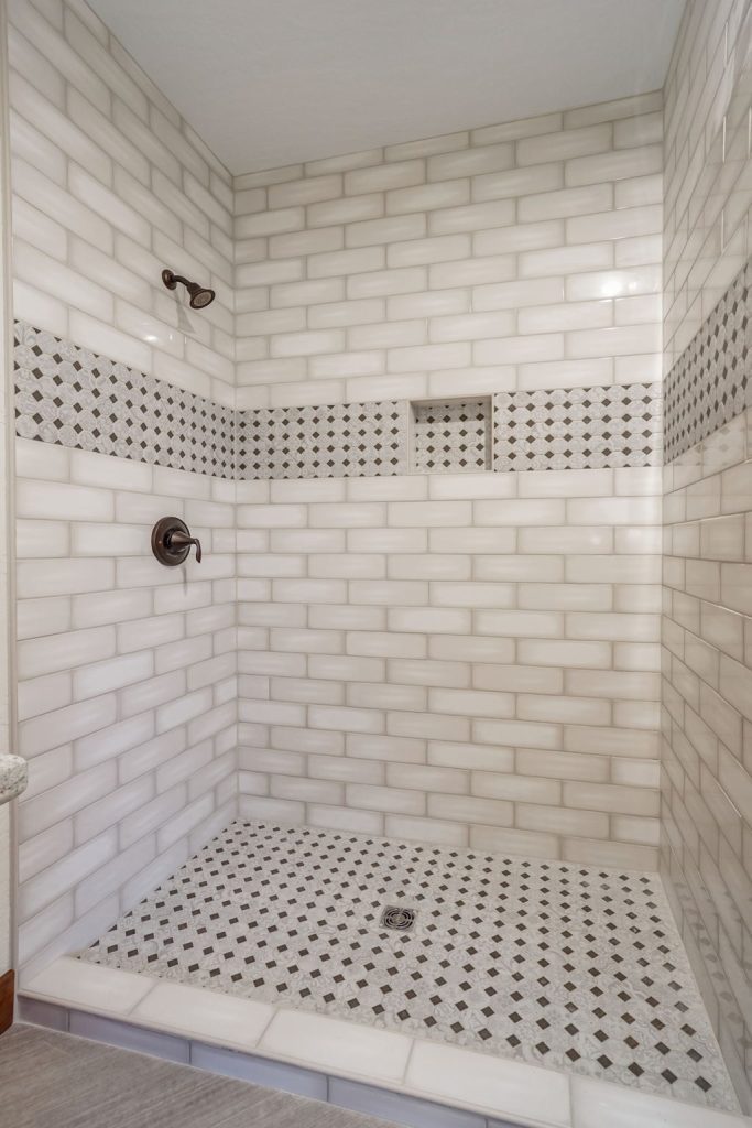 A white tiled shower with a tiled floor.