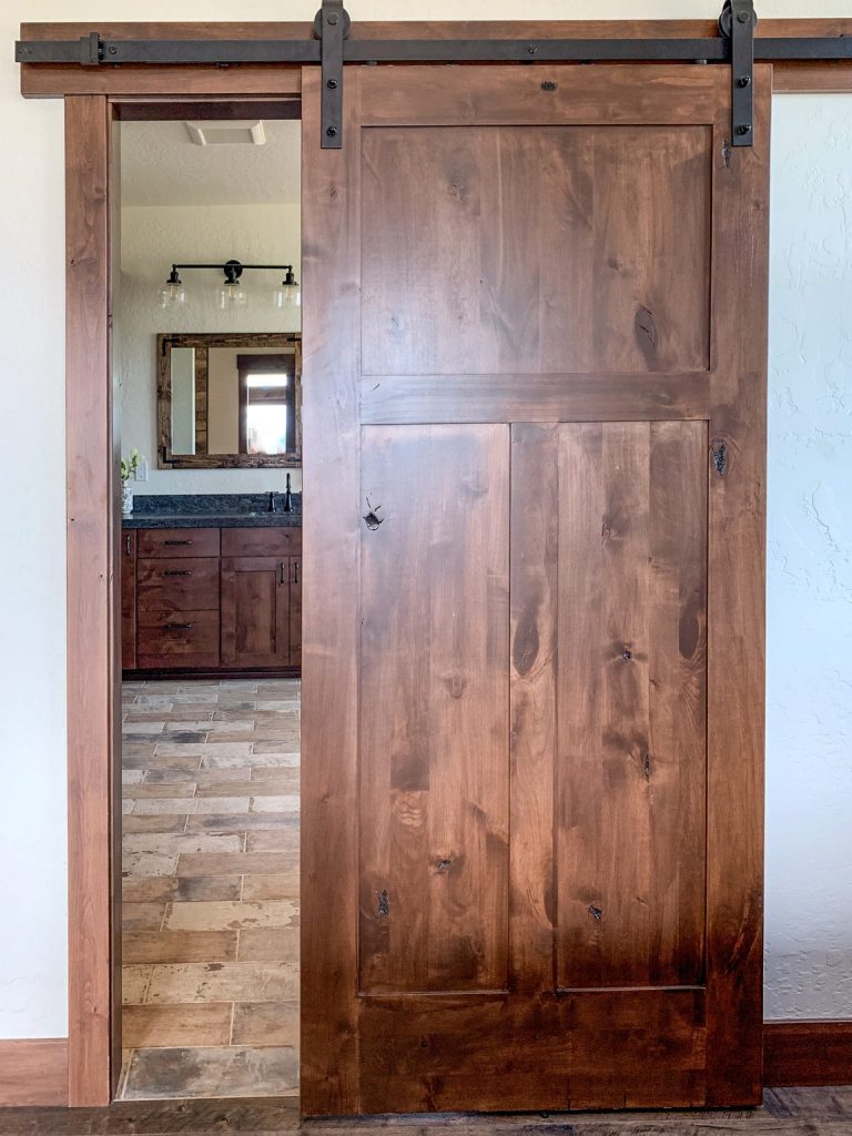 A wooden sliding barn door in a bathroom.