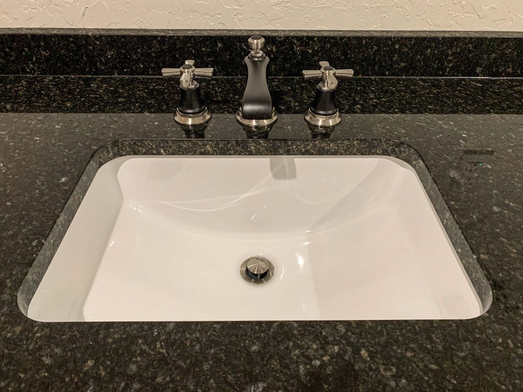 A bathroom sink with a black granite counter top.
