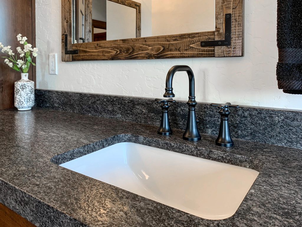 A bathroom with a granite counter top and a mirror.