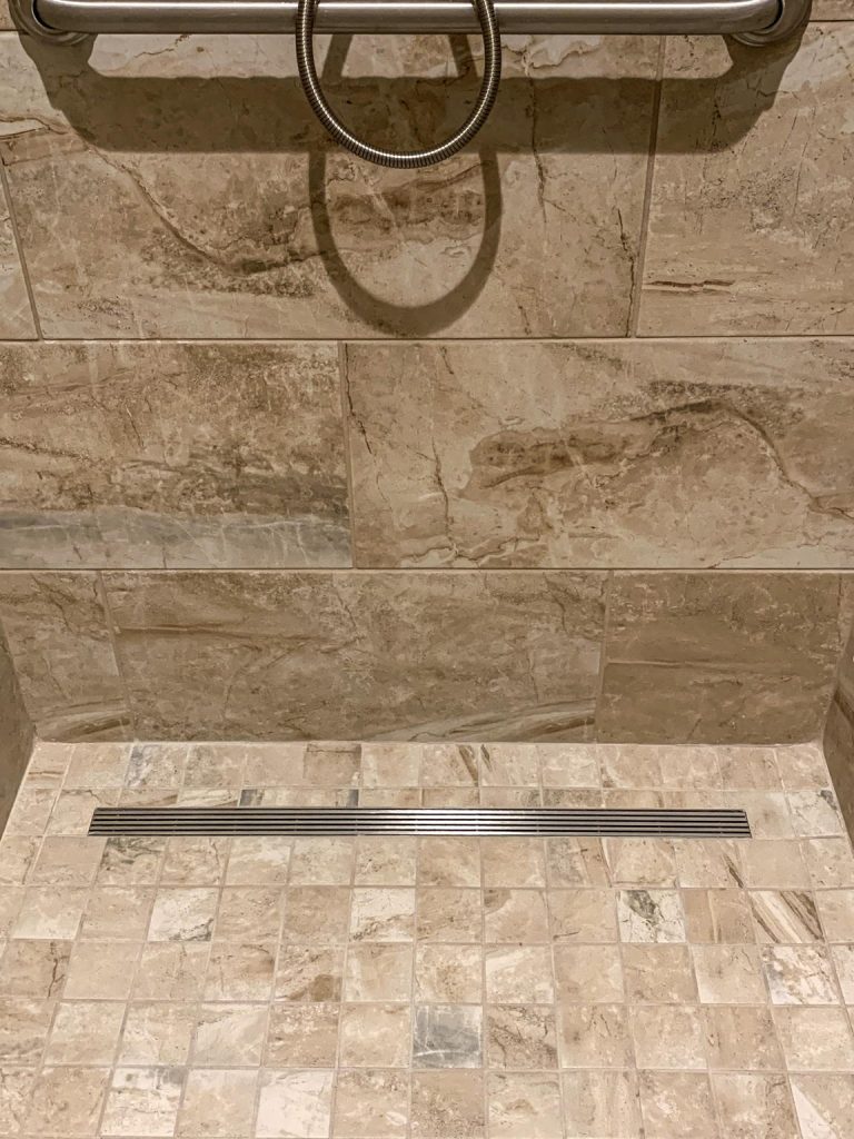 A shower with a tiled floor and a handrail.