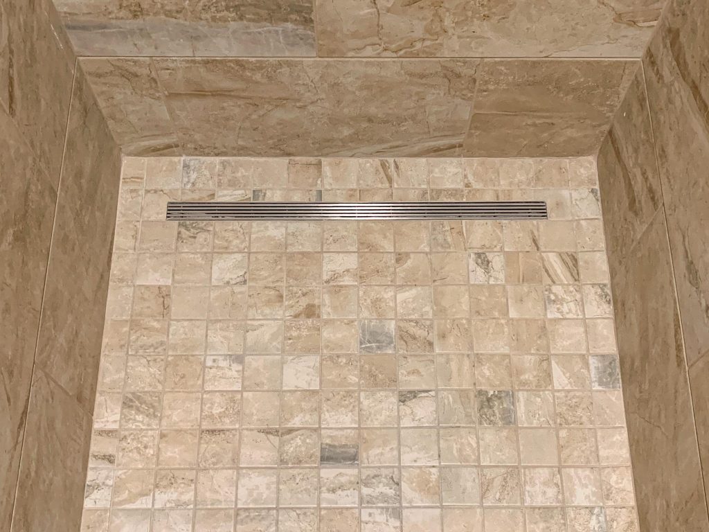 A shower with a beige tiled floor.
