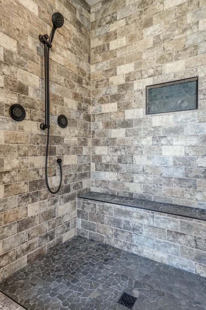 A shower with a stone wall and a shower head.