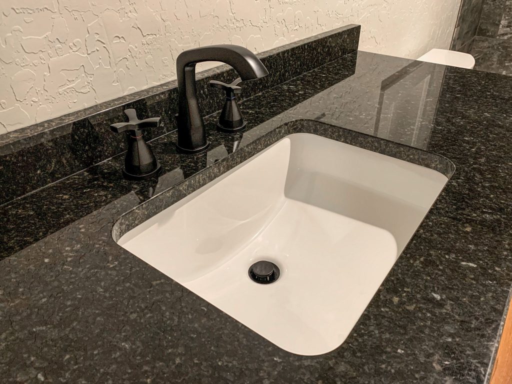 A bathroom sink with black granite counter tops.