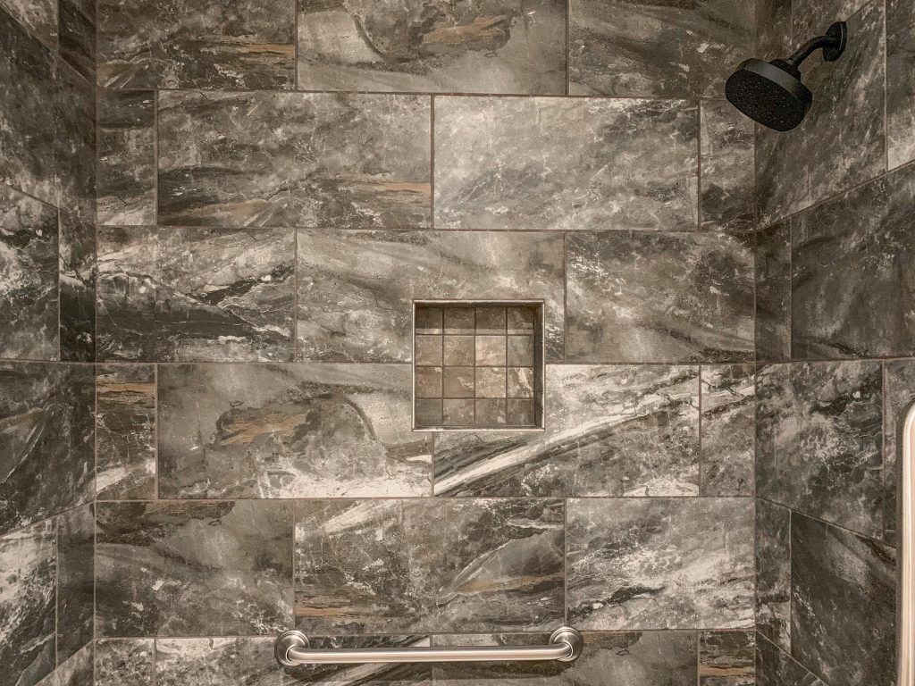 A shower with a gray tiled floor and a shower head.