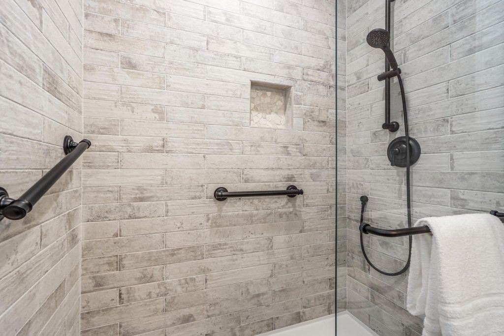 A bathroom with a glass shower door and a hand rail.