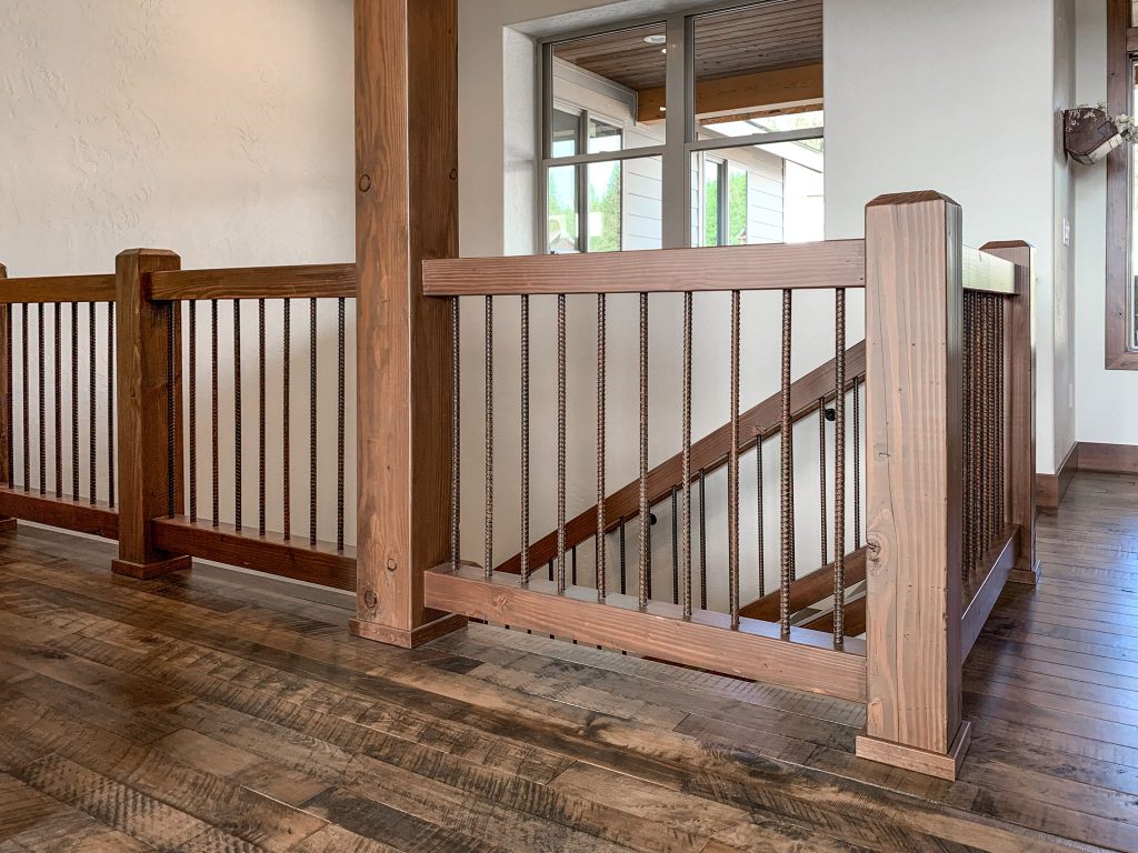 A wooden railing in a home with hardwood floors.