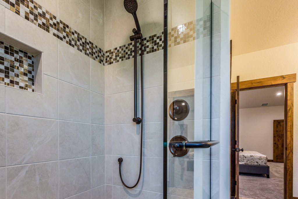 A bathroom with a glass shower door and tiled floor.