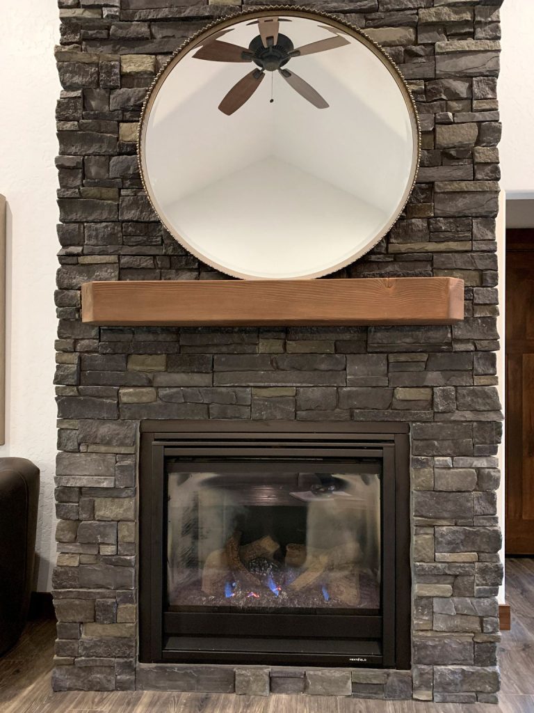 A stone fireplace with a mirror above it.
