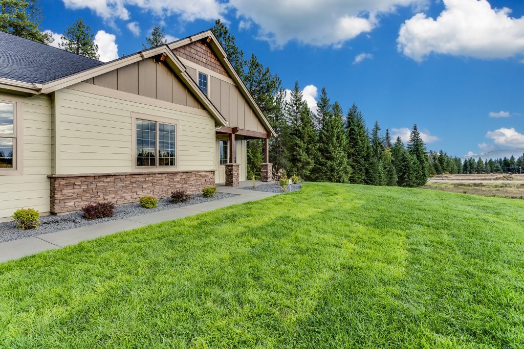 A home with a grassy yard and trees in the background.