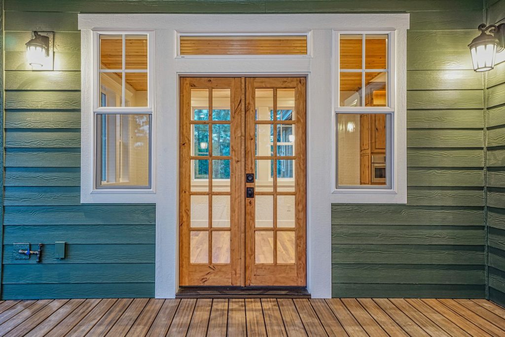 A front porch with a green door and wooden floor.