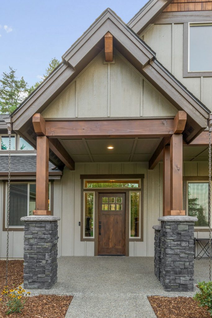 A home with a wooden front porch and stone pillars.
