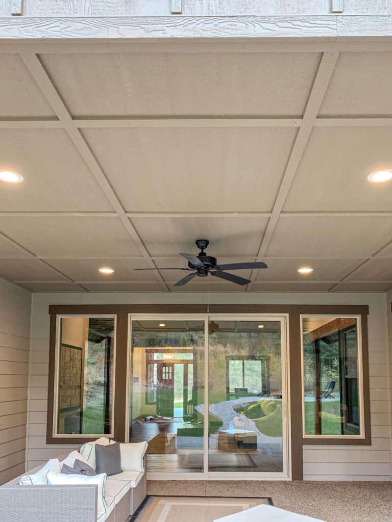 An outdoor living room with a ceiling fan and sliding glass doors.