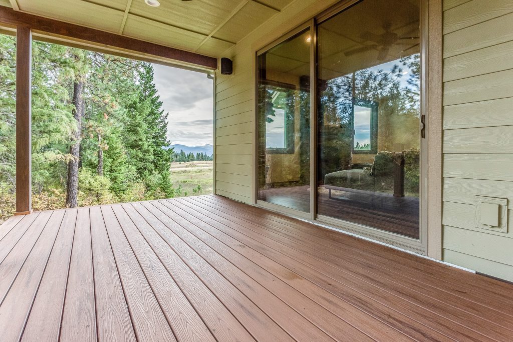 A wooden deck with sliding glass doors overlooking a wooded area.