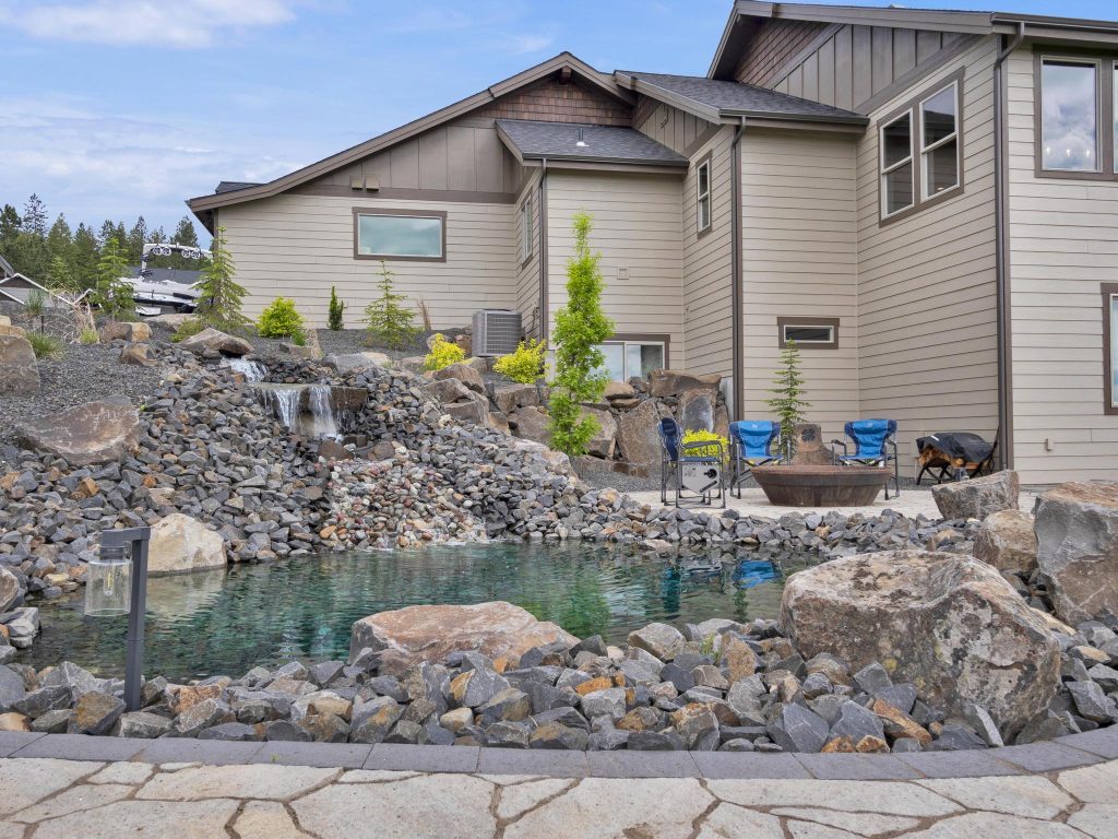 A home with a pond and rocks in front of it.