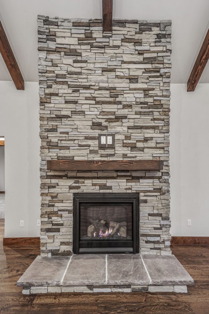 A stone fireplace in a living room with wood beams.