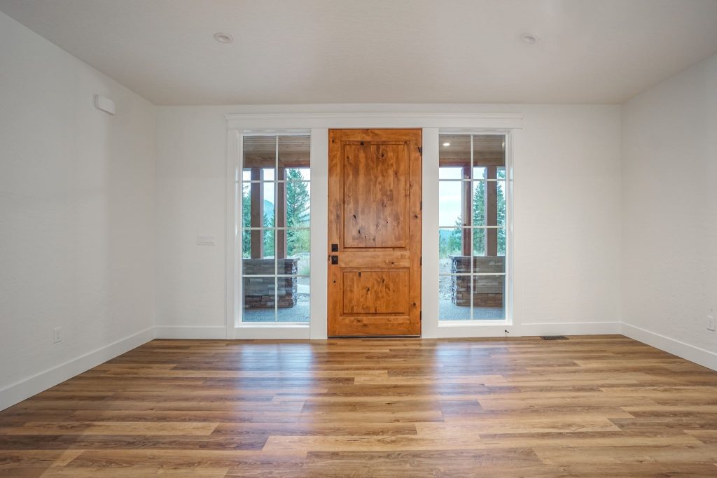 An empty room with wood floors and a wooden door.