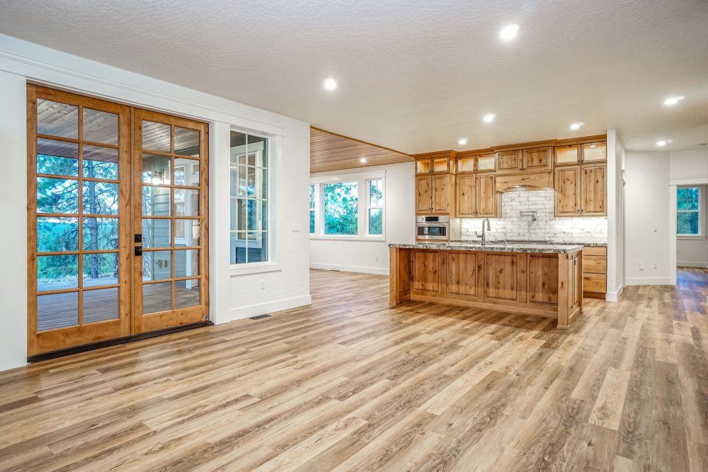 An empty kitchen with wood floors and a sliding glass door.