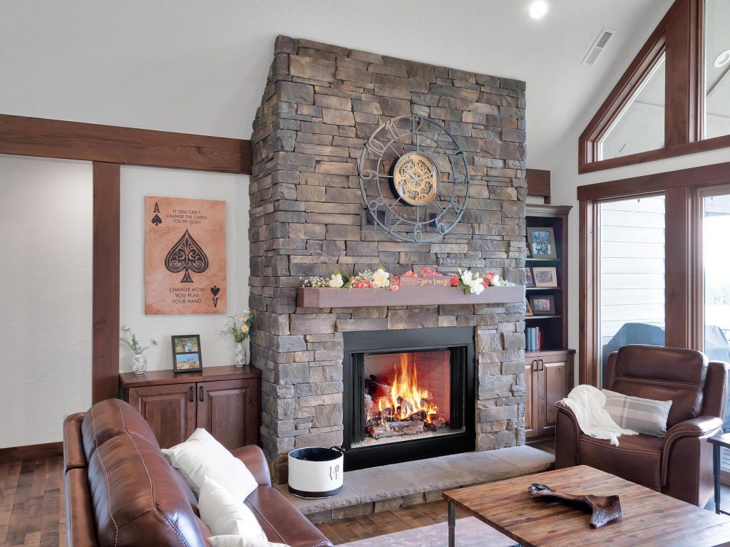 A living room with a stone fireplace and leather furniture.