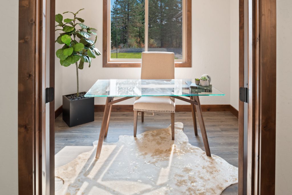 A home office with a glass desk and a cowhide rug.