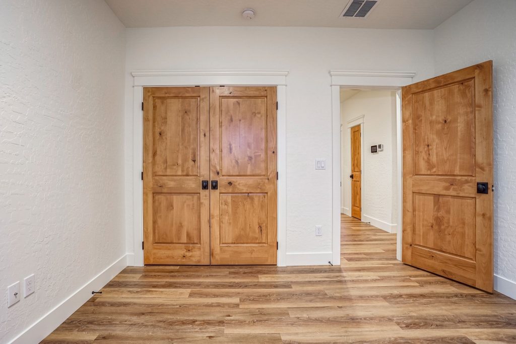 An empty room with wooden doors and hardwood floors.