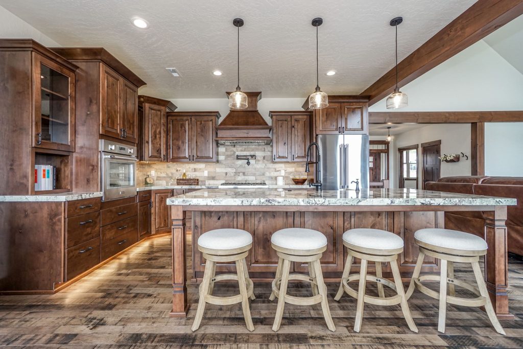 A large kitchen with wood cabinets and stools.