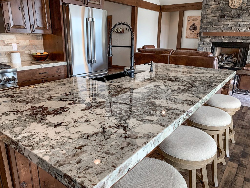 A kitchen with granite counter tops and stools.