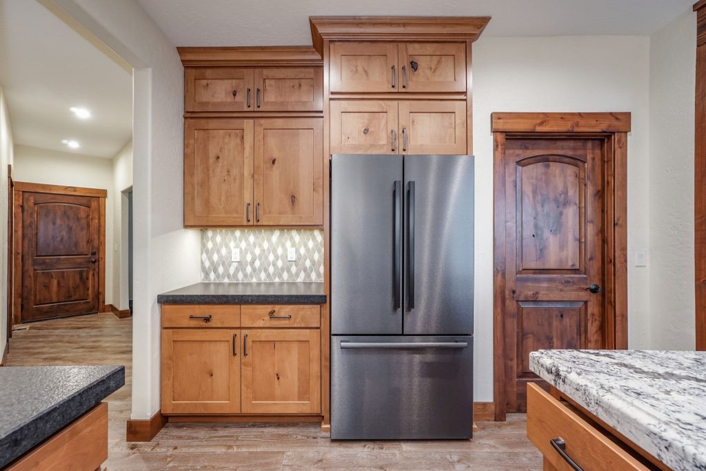 A kitchen with wood cabinets and a stainless steel refrigerator.