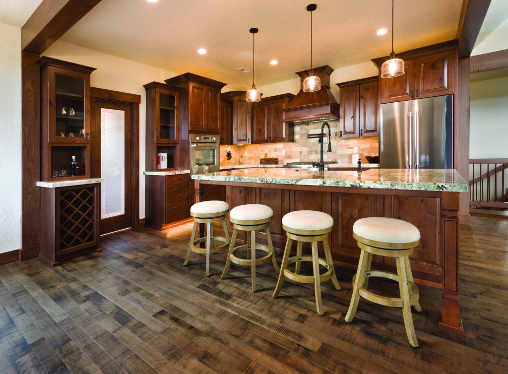 A kitchen with wood floors and stools.