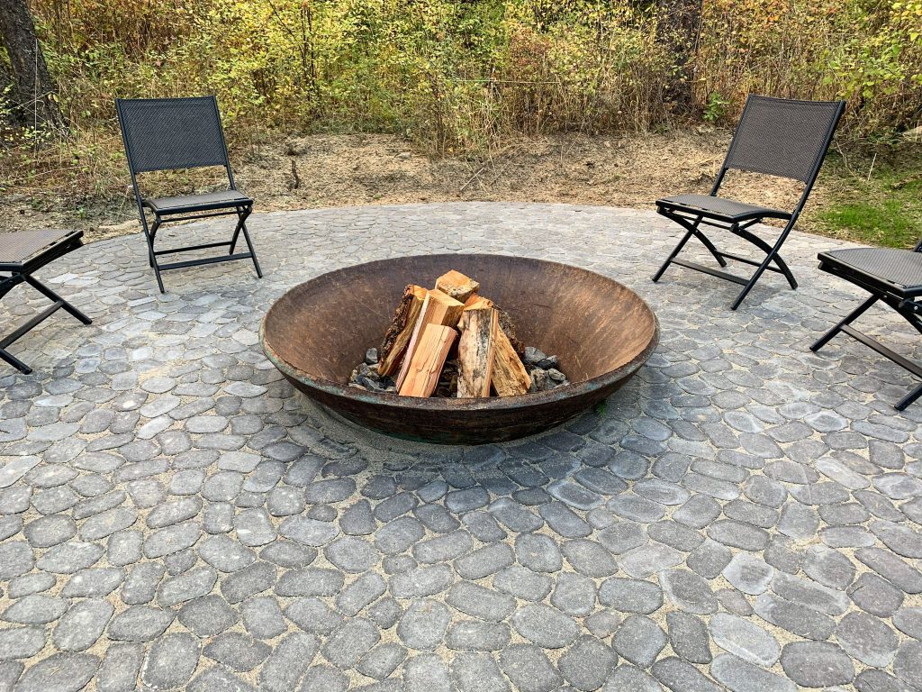 A fire pit with chairs sitting around it.