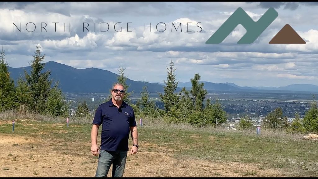 A man standing in front of a hill with the words north ridge homes.